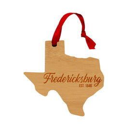 Wooden Texas shaped ornament with Fredericksburg on it and a red ribbon hanger